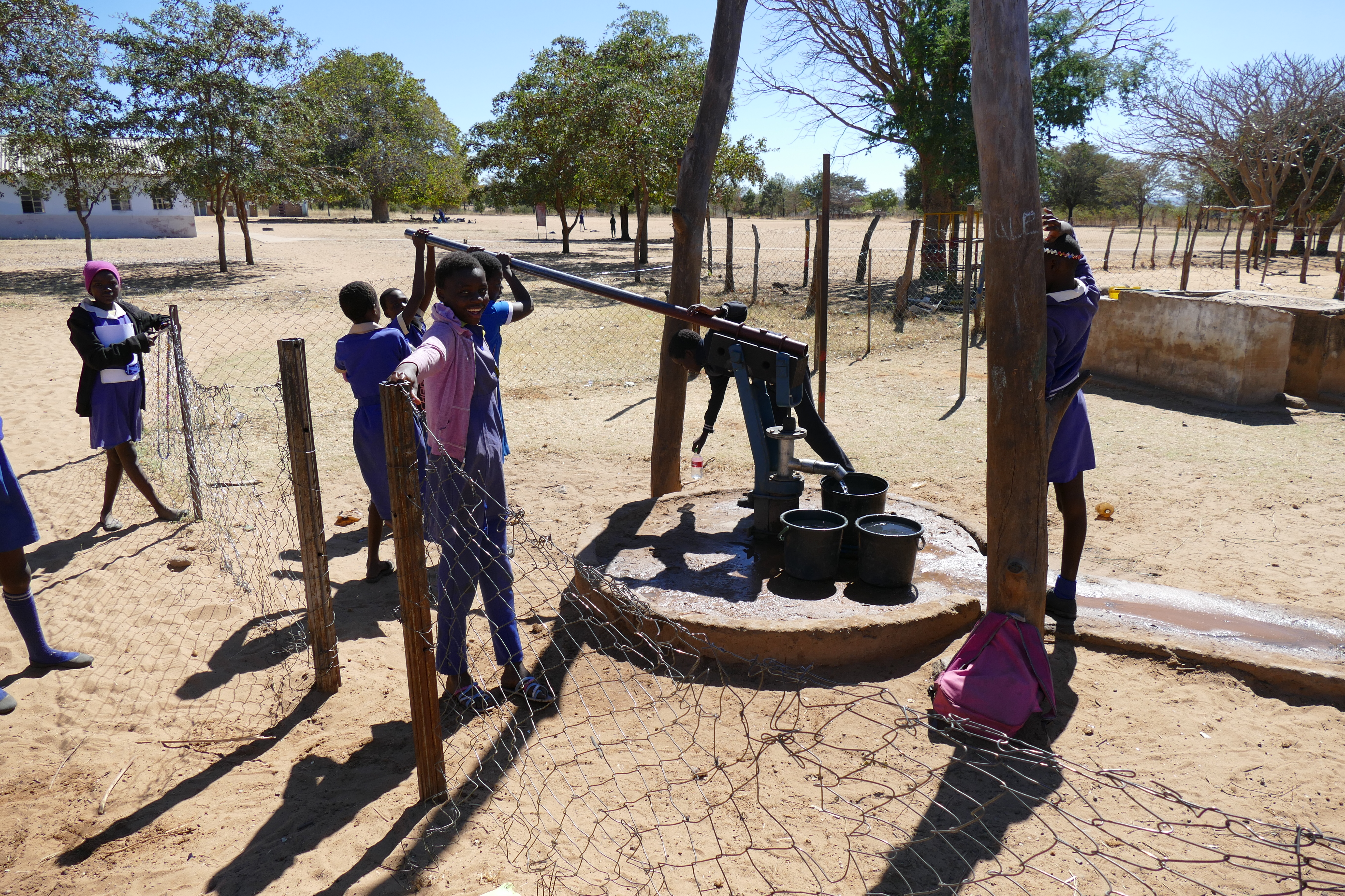 Monde community children working together to pump water to bring back to their homes
